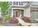 Inviting covered porch with stone details, featuring a red door and a comfortable white rocking chair at 2625 Rea Pond Ct, Charlotte, NC 28226