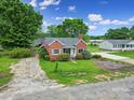 Quaint brick home with mature landscaping, a gray roof, and light blue shutters surrounded by lush green grass and trees at 5573 Main St, Fort Lawn, SC 29714