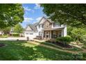 Beautiful two-story home with a well-manicured lawn, stone accents, and a cozy front porch at 7730 Windsor Forest Pl, Harrisburg, NC 28075