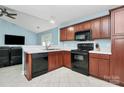 Functional kitchen with wood cabinets and black appliances and tile floors at 9212 Scotts Elm Ct, Charlotte, NC 28215