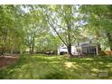 A spacious lawn with mature trees surrounds a charming white house with a screened porch at 1023 Evian Ln, Matthews, NC 28105