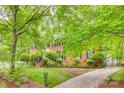Traditional brick home with manicured lawn, mature trees, and a gated driveway at 1023 Evian Ln, Matthews, NC 28105