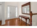 Bright entryway featuring hardwood floors, classic console table with decorative mirror, and elegant front door at 12802 Waterlyn Club Dr, Charlotte, NC 28278