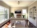 Bright home office featuring a large desk, modern lighting, and ample natural light with two large windows and built in shelving at 16446 Doves Canyon Ln, Charlotte, NC 28278
