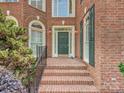 Charming entrance featuring a brick walkway, elegant sconces and a classic green front door at 16511 Bridgehampton Club Dr, Charlotte, NC 28277