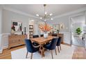 Formal dining room with stylish chandelier, wood table, blue chairs, and detailed trim at 2345 Sparrow Dr, Rock Hill, SC 29732