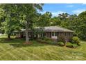 Beautiful brick house with mature trees, a well-manicured lawn, and lush landscaping providing excellent curb appeal at 2410 Armstrong Park Dr, Gastonia, NC 28054