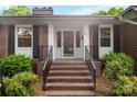 Inviting brick front entrance with black shutters and decorative door, framed by lush landscaping at 2410 Armstrong Park Dr, Gastonia, NC 28054