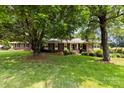 Charming brick home with mature trees, lush green lawn and inviting front porch at 2410 Armstrong Park Dr, Gastonia, NC 28054