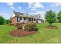 Beautiful brick house complemented by a lush green lawn, colorful flower beds, and an attached garage at 34843 Ellis Spring Ct, Albemarle, NC 28001