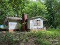 A house overgrown with weeds is boarded up at 455 Running Brook Rd, Midland, NC 28107