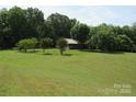 Expansive lawn leading to a cozy single-story home surrounded by mature trees, offering privacy and a serene setting at 5908 Tanson Trl, Marshville, NC 28103