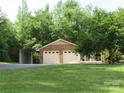 Well-maintained two-car garage with brick facade and lush green lawn with mature trees in the background at 5908 Tanson Trl, Marshville, NC 28103