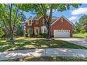 Charming brick home with manicured lawn, tree, and an attached two-car garage, great curb appeal at 8211 Abbottsgate Ln, Charlotte, NC 28269