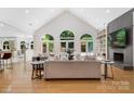 Open living room with hardwood floors, large windows, vaulted ceiling, fireplace, and view of the pool at 1245 Bellemeade Ln, Charlotte, NC 28270