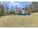Exterior view of a cozy, white cottage-style home on a large, grassy lot with mature trees at 1339 Hill St, Albemarle, NC 28001