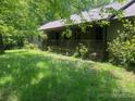 View of front exterior featuring covered porch, wood siding, and a well-maintained grassy lawn at 1502 Shelby Hwy, Cherryville, NC 28021