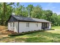 A side view of the freshly painted white brick home and manicured lawn surrounded by mature trees at 1820 Shannonhouse Dr, Charlotte, NC 28215