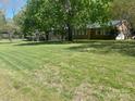 Large yard with mature trees surrounding a brick home with ample windows and attached garage at 205 Rudolph Rd, Salisbury, NC 28146