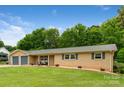 A charming ranch-style home features a well-kept lawn, brick accents, and a tranquil, tree-lined backdrop at 213 Lakeview Dr, Harrisburg, NC 28075
