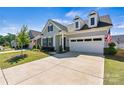 Beautiful gray house featuring neat landscaping, a two-car garage, and an American flag at 213 Warbler Dr, Monroe, NC 28110