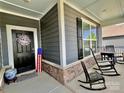 Inviting covered porch offers rocking chairs, views, and an American flag, enhancing the home's curb appeal at 6266 Swanport Rd, Lancaster, SC 29720