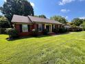 A cozy brick house featuring lush green grass, black shutters, and a well-maintained landscape at 6301 Cherrycrest Ln, Charlotte, NC 28217