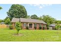 Charming single-story brick home with well-manicured lawn, mature trees and trimmed shrubs at 6301 Cherrycrest Ln, Charlotte, NC 28217