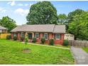 Charming single-story brick home with well-manicured lawn, detached garage and fenced driveway at 6301 Cherrycrest Ln, Charlotte, NC 28217