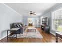 Inviting living room featuring hardwood floors, soft blue walls, a ceiling fan, and many windows at 6301 Cherrycrest Ln, Charlotte, NC 28217