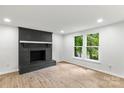 Living room with black brick fireplace, white walls, and newer wood look flooring at 6839 Wagon Oak Rd, Charlotte, NC 28212