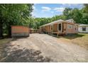 Charming single-story home featuring gravel driveway and spacious backyard, nestled among mature trees at 908 Taylor St, Kannapolis, NC 28083