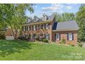 Charming two-story brick home featuring black shutters, dormers, mature landscaping, and a well-manicured lawn at 9513 Tresanton Dr, Charlotte, NC 28210