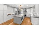 Spacious kitchen showcasing white cabinetry, a large center island, stainless steel appliances, and hardwood floors at 9513 Tresanton Dr, Charlotte, NC 28210