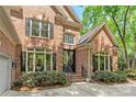 Close up of an elegant brick home with large windows, dark shutters, and a well-manicured front garden at 11510 Pine Valley Club Dr, Charlotte, NC 28277