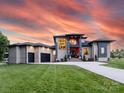 Stunning modern home featuring a two-car garage, well-manicured lawn, and elegant architectural design under an orange sunset at 4315 Hartis Grove Church Rd, Indian Trail, NC 28079