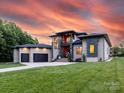 Stunning modern home featuring a two-car garage, well-manicured lawn, and elegant architectural design under an orange sunset at 4315 Hartis Grove Church Rd, Indian Trail, NC 28079