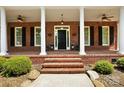 Close up of front door of brick home featuring brick steps, columns, and outdoor lighting at 4570 Chanel Ct, Concord, NC 28025