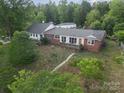 Aerial view of a single-story brick home with a wooden deck and a lush, green yard at 565 Shore Acres Rd, Salisbury, NC 28146