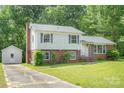 View of the home's side yard and driveway, with mature landscaping and a storage shed at 7106 Marlbrook Dr, Charlotte, NC 28212