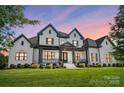 Gorgeous white home with black trim and covered porch bathed in soft evening light at 1005 Grand Oak Dr, Waxhaw, NC 28173