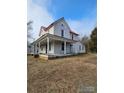 Two-story home featuring a red roof and an inviting wrap-around porch, perfect for outdoor living and relaxation at 105 E Second Ave, Mount Gilead, NC 27306
