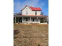 Charming two-story home with a red roof and inviting wrap-around porch, blending classic design with outdoor living at 105 E Second Ave, Mount Gilead, NC 27306