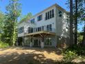Stunning home exterior with spacious balconies, large windows, and a modern design nestled among mature trees at 124 Clipper Ln, Mooresville, NC 28117