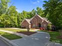 Charming brick home with circular driveway, manicured lawn, and blooming flowers creating picturesque curb appeal at 130 Churchill Dr, Salisbury, NC 28144