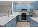 Modern kitchen featuring quartz counters, stainless steel appliances and vibrant blue cabinets offering a gourmet experience at 16610 Amberside E Rd, Cornelius, NC 28031