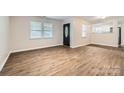 Bright living room with wood-look flooring, neutral walls, and natural light from two windows at 2424 Pitts Dr, Charlotte, NC 28216