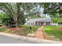 Inviting home featuring a red brick pathway, lush lawn, and mature trees at 5601 Carmel Station Ave, Charlotte, NC 28226