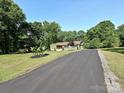 Long driveway leading to a green home with manicured lawns and mature trees at 9565 Man O War Rd, Indian Land, SC 29707
