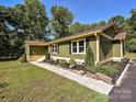 Green home with black shutters, well-maintained landscaping, and a concrete walkway at 9565 Man O War Rd, Indian Land, SC 29707